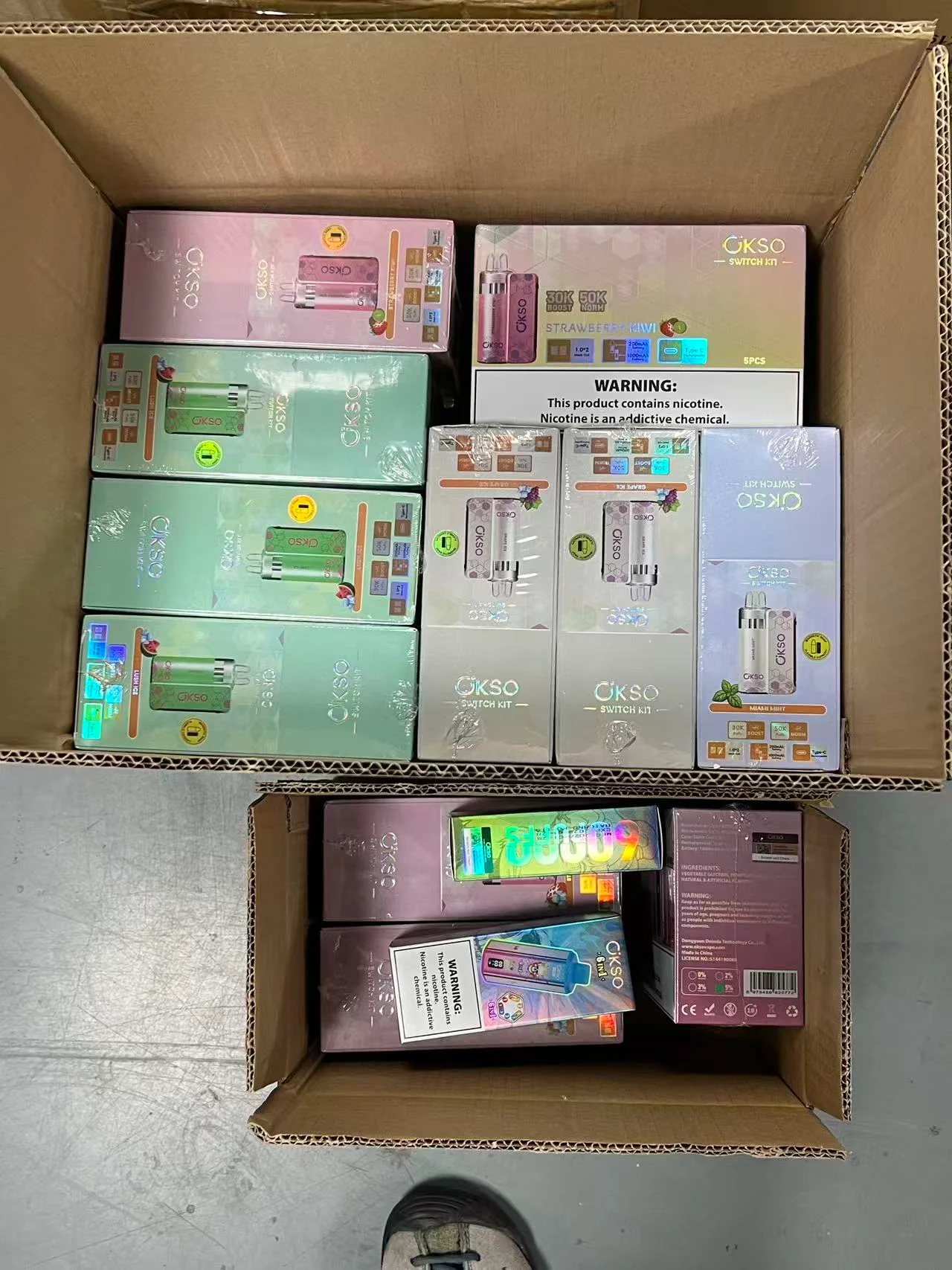 A small stack of boxes next to a large pallet of boxes.